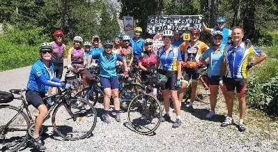 Une vingtaine de cyclistes du club, hommes et femmes, posent au sommet d'un col devant le panneau.