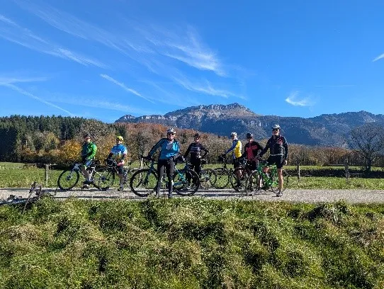 Une douzaine de cyclistes du club en maillots bleus sur une petite route, devant les falaises calcaires de la Chartreuse en automne.