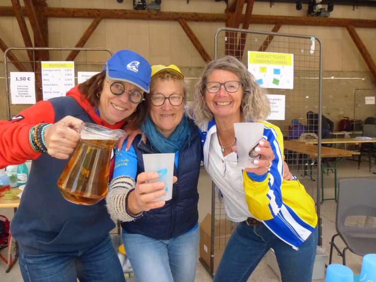 Trois bénévoles de la Coublevitaine, rieuses, trinquent avec un pichet et des gobelets au ravitaillement.