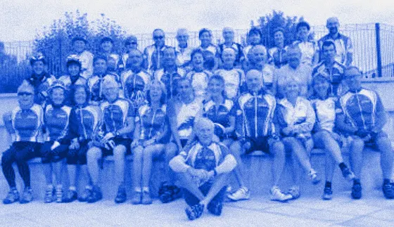 Photo de groupe d'une quarantaine d'adhérent·es en maillot du club bleu, jaune et blanc, assis sur des marches.